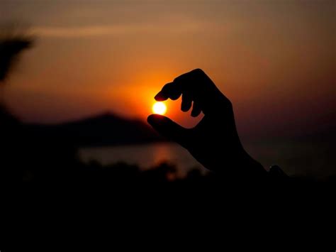 Premium Photo A Hand Catches The Sun Closeup Silhouette Reaches Out