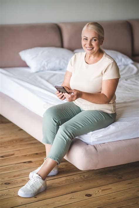 Cheerful Modern Mature Woman Using The Cellphone In The Bedroom Stock Photo Image Of Bedding