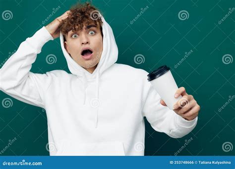 A Shocked Man Stands On A Green Background In A White Hoodie Holding A