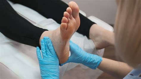 Skilled Female Masseur Giving Foot Massage To Young Woman At Beauty