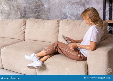 Blonde Woman Sitting On Couch Using Tablet At Home In The Living Room Stock Image Image Of