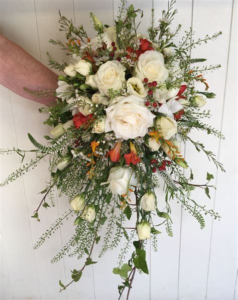 A Bridal Bouquet With White Roses And Greenery On The Side Of A Wall