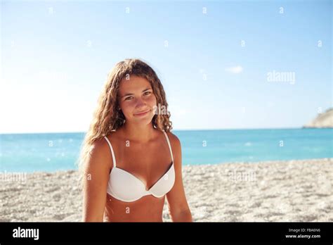 Junge blonde Mädchen lächelnd an einem weißen Strand mit weißen Bikini