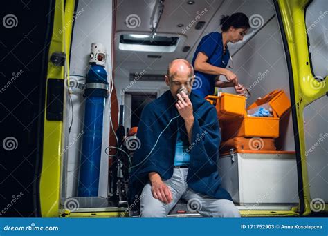 Man In Blanket Breathe Through Oxygen Mask Nurse Packs Equipment In