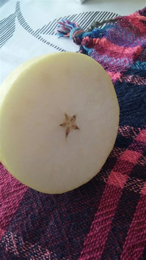 An Apple Sliced In Half Sitting On Top Of A Plaid Cloth With A Star Cut