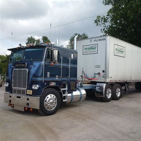 A Semi Truck Is Parked In A Parking Lot With A Trailer Attached To The Back