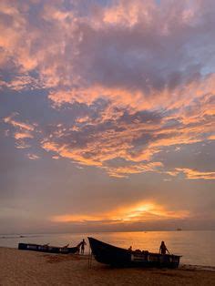 Two Boats Sitting On Top Of A Sandy Beach Under A Cloudy Blue And Pink Sky