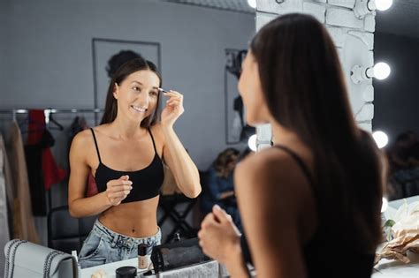 Reflexo De Uma Bela Jovem Aplicando Sua Maquiagem Olhando No Espelho