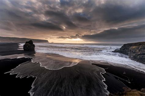 Download Relaxing On A Dramatic Black Sand Beach Wallpaper