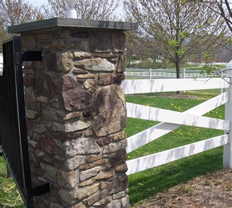 A Stone Pillar In Front Of A White Fence