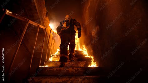 Strong And Brave Firefighter Going Up The Stairs In Burning Building