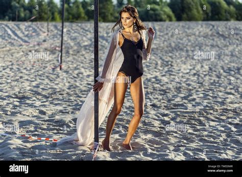 Attractive Brunette Woman In Black Body And Translucent Beach Cover Up Posing On Sandy Beach At