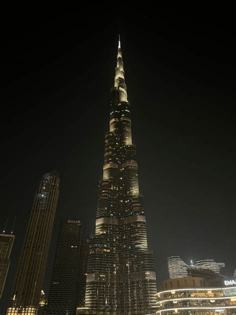 The Burj Building Is Lit Up At Night With Lights On It S Sides