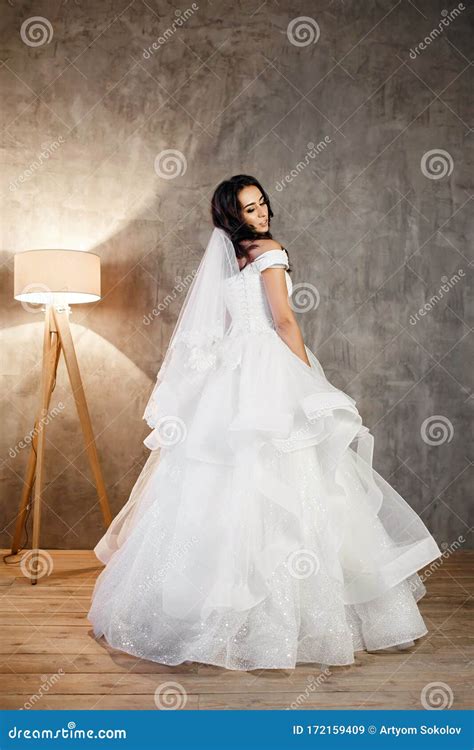 Beautiful Bride In A White Wedding Dress On A Gray Wall Background