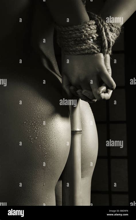 Naked Woman With Her Hands Tied To A Bamboo Stick Stock Photo Alamy