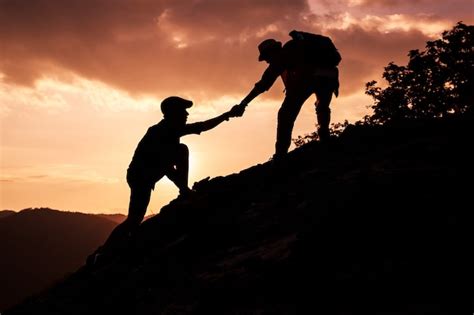 Silhueta De Alpinista Ajudando Uns Aos Outros A Escalar Uma Montanha