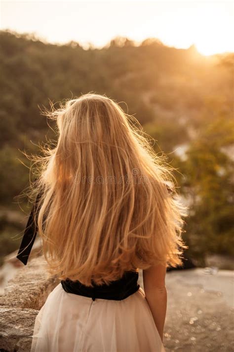 Blonde With Long Hair On A Sunny Seashore In A Red Flowing Dress Back View Silk Fabric Waving