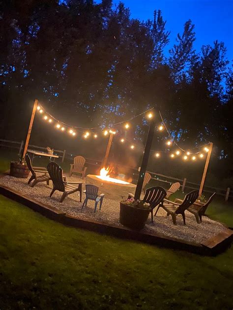 an outdoor fire pit surrounded by chairs and string lights