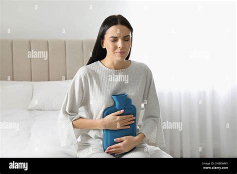 Woman Using Hot Water Bottle To Relieve Abdominal Pain On Bed At Home Stock Photo Alamy