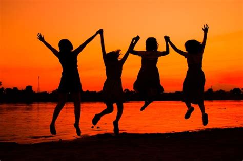 Silhueta De Mujeres Con Los Brazos Levantados Saltando En La Playa