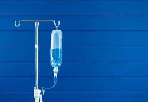 Premium Photo Saline Bag Hanging On Poles Stand Isolated On Blue Wood