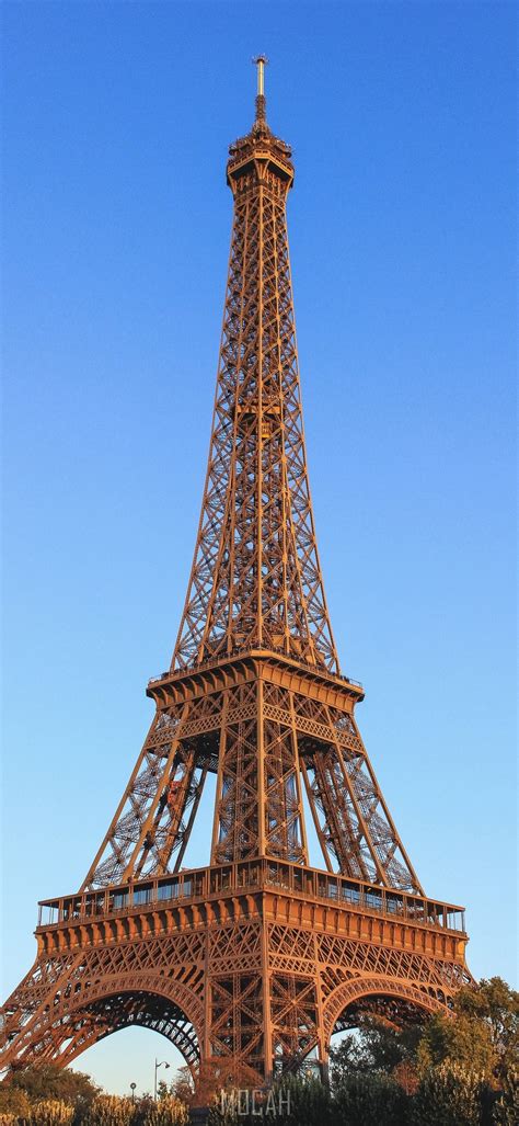 A Full View Of The Eiffel Tower In Paris With Clear Blue Skies Behind