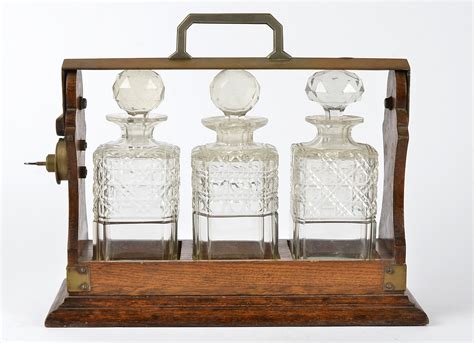 An Oak Framed Tantalus Containing Three Cut Glass Decanters With Key