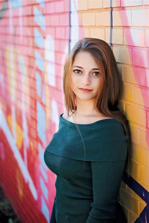 A Woman Leaning Against A Brick Wall With Graffiti On It S Walls Behind Her