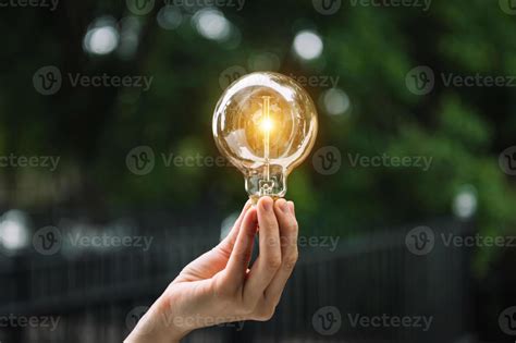 Hand Holding Light Bulb With Green Background Idea Solar Energy In