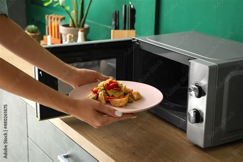 Woman heating food in microwave oven Stock Photo | Adobe Stock