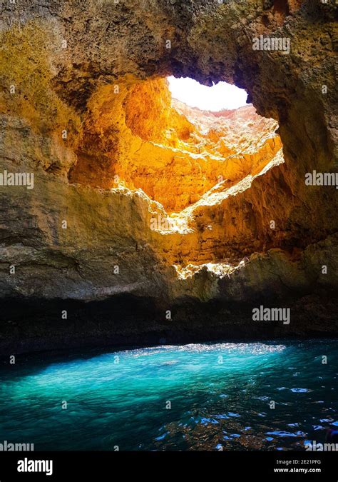 Sun goes through a hole of the Benagil Cave, Portugal, giving a spectacular blue color to the ...