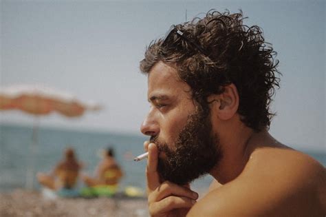 Close Up De Um Homem Sem Camisa Fumando Um Cigarro Na Praia Foto Premium