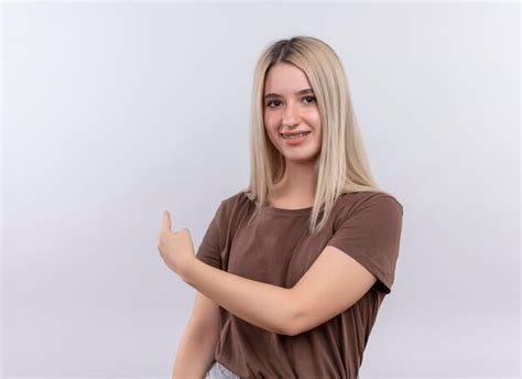 Souriante Jeune Fille Blonde Dans Un Appareil Dentaire Pointant Derrière Sur Un Espace Blanc