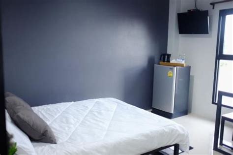 A White Bed Sitting In A Bedroom Under A Flat Screen Tv Next To A Window