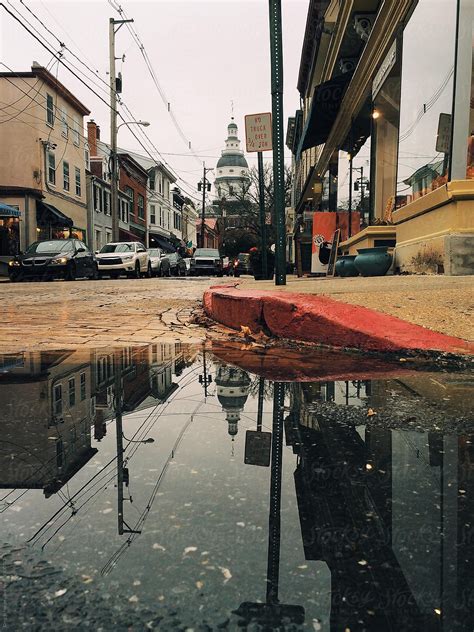 "A Small Town Street With A Reflection Of A Domed Building In A Rain