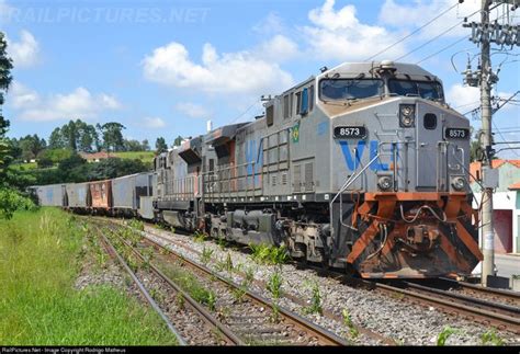 A Train Traveling Down Tracks Next To A Lush Green Field