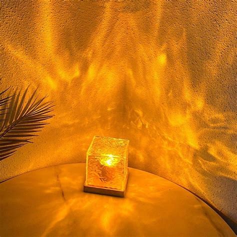 A Lit Candle Sitting On Top Of A Round Table Next To A Plant And Wall