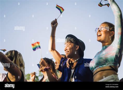 Happy Man And Woman With Hands Raised Holding Rainbow Flags While Enjoying In Gay Pride Parade