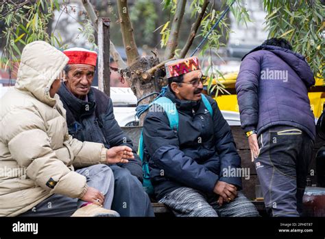 Men in traditional himachal pradesh caps and jackets discuss something ...