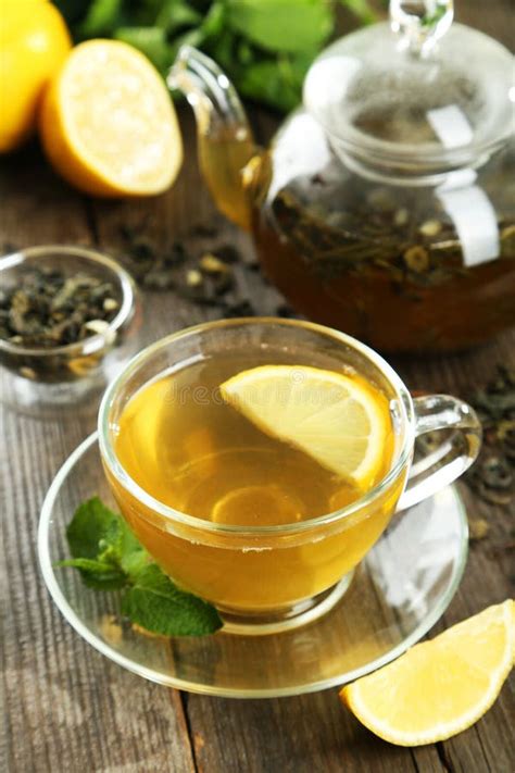 Зеленый чай в чашке и чайнике на коричневой деревянной предпосылке ...