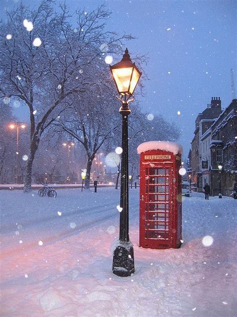 A Red Phone Booth Sitting In The Middle Of A Snow Covered Park Next To