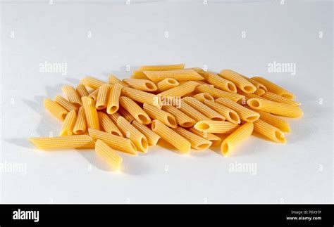 Sin cocer la pasta penne rigate contra un fondo blanco Fotografía de