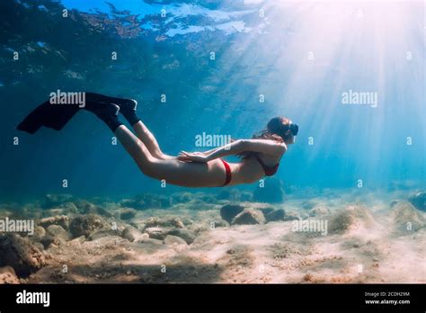 Slim Woman In Bikini Glides At Blue Sea With Sun Rays Freediving With