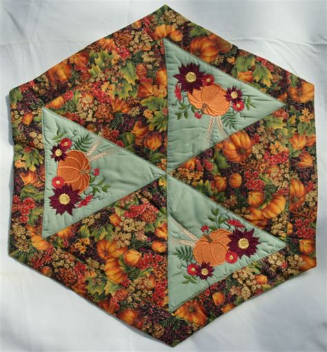 A Quilted Table Topper With An Orange Turkey And Flowers Design On The Center