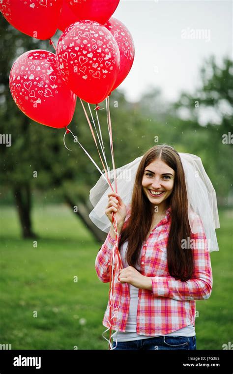 Portrait Of Brunette Girl On Checkered Shirt Jeans And Veil With Many Red Balloons At Hen Party