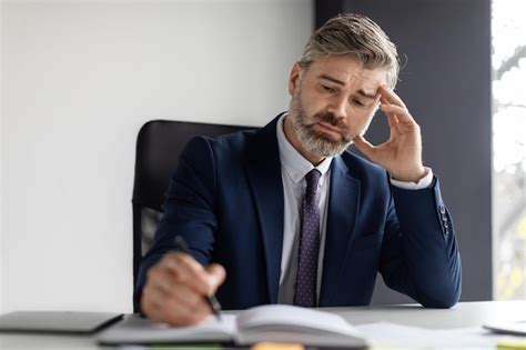 Empresario De Mediana Edad Sentado En El Escritorio En La Oficina Y