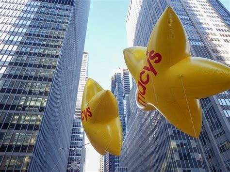 Two Large Yellow Star Shaped Balloons Floating In The Air Next To Tall