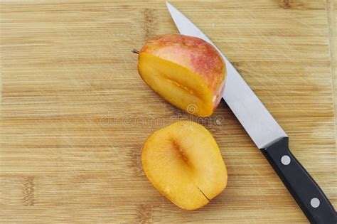 Un Corte De Pluot Del Amigo Abierto Con Un Cuchillo En Una Tajadera De