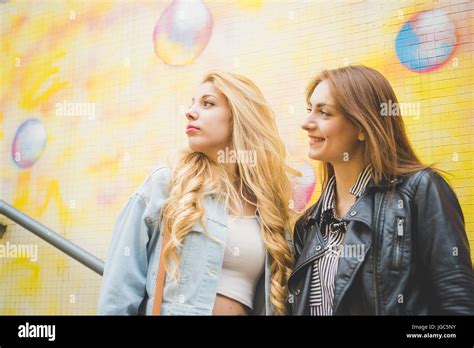 Two Beautiful Blonde And Brunette Girls Posing And Having Fun On A Colorful Subway Stock Photo