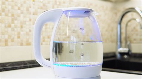 Transparent electric kettle with boiling water on table in kitchen ...